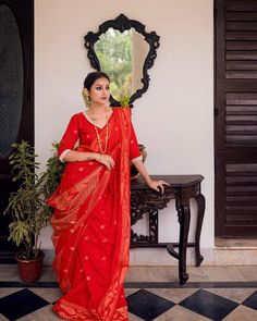 a woman in a red sari standing next to a mirror