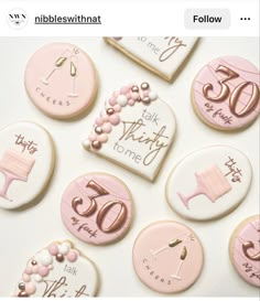 cookies decorated with pink and gold icing are displayed on a white tablecloth that says, 50th