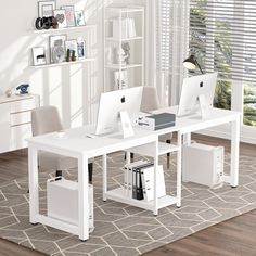 a white desk with two computers on it in front of a book shelf filled with books