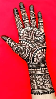 the hand is decorated with black and white henna designs on red background stock photo