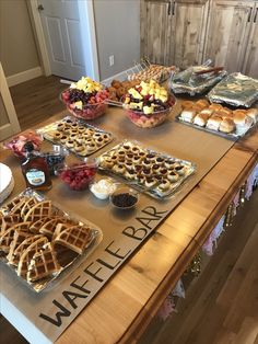 a wooden table topped with lots of waffles and other foods on top of it