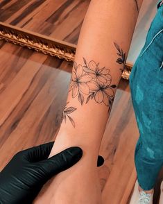 a woman's arm with flowers on it and a black glove next to her