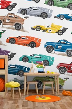 a child's room with colorful cars on the wall and wooden table in front