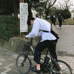 a man riding a bike down a street next to a sign with writing on it