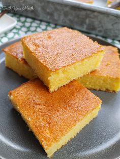 three pieces of cake sitting on top of a plate next to a pan filled with other food