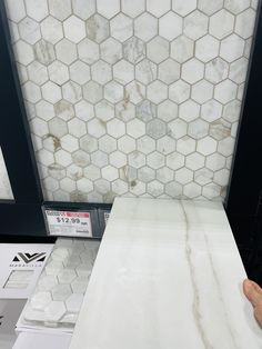 a counter top in a store with white marble tiles on the wall and flooring behind it