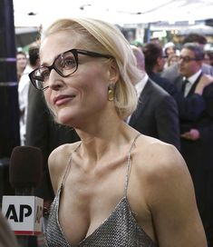 a woman wearing glasses talking to someone on the red carpet