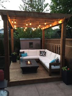 an outdoor living area with couches, tables and lights on the roof above it