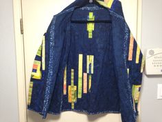 a blue jacket with yellow and green strips on it hanging from a hook in a door