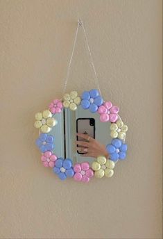 a hand holding a cell phone in front of a mirror with colorful buttons on it