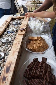 some people are standing at a table with food on it and plates full of marshmallows