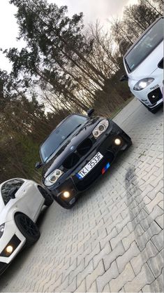 two cars parked next to each other on a brick road