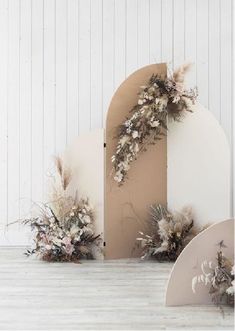 an arch with dried flowers on it next to another arch that has been cut out