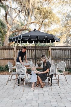 a family sitting around a table under an umbrella