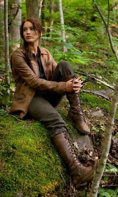 a woman sitting on top of a moss covered forest