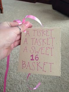 a hand holding a piece of paper with pink writing on it that says, a tisket is a sweet 16 basket