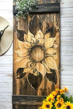 a sunflower is painted on the side of a wooden door with a straw hat next to it