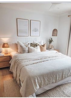 a white bed sitting next to two lamps on either side of a window in a bedroom