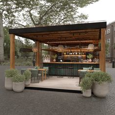 an outdoor bar with potted plants on the side and tables in front of it