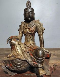 a bronze statue sitting on top of a wooden table