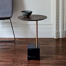 a black table with a bowl on it and a grey chair in the corner behind it