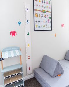 a child's room with a large growth chart on the wall next to a couch