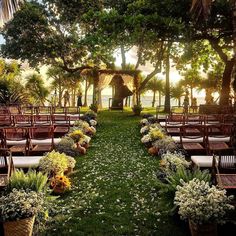 an outdoor ceremony set up with chairs and flowers on the grass in front of trees