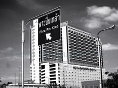 a black and white photo of a tall building with a sign in the foreground