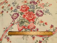 a measuring tape is on top of a floral print fabric with red, pink and blue flowers