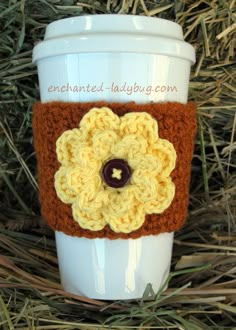 a coffee cup sleeve with a crocheted flower on the front and brown trim around it