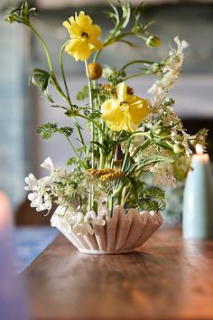 a vase filled with flowers sitting on top of a wooden table next to a candle