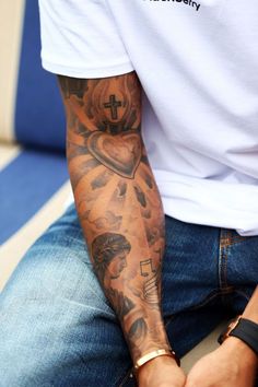 a man with tattoos on his arm sitting down