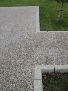 an empty sidewalk with grass and trees in the background