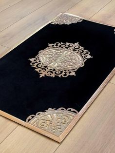 a black area rug with gold trimmings on top of wooden flooring in an empty room