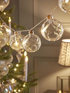 a christmas tree with clear glass ornaments hanging from it's sides and lights on the branches