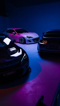 three cars in a dark room with purple lighting