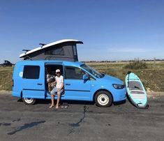 a man standing next to a van with surfboards