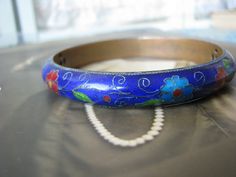 A beautiful antique Chinese Export cobalt blue cloisonne bangle bracelet. As you see, it is decorated in a simple flower and foliage design. The cobalt is real on this bracelet and is a very fine consistency. It is not a cheap imitation sand has almost a translucent quality to it! This bangle is especially nice due to it having a bronze base instead of the common brass base. Measures over 3/8'' wide and 5mm thick. It also measures over 2 1/2'' across the inside and 8 1/2'' along the inside. This Antique Blue Bracelet As Gift, Antique Blue Round Bracelets, Art Deco Locket, Wedding Tokens, Nottingham Lace, Sewing Lace, Halloween Bottles, Chinese Jewelry, Round Locket