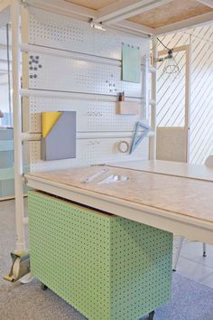 an office desk with pegboard on the wall next to it and shelves in the background