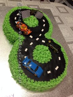 a birthday cake with cars on it and the number six made out of green grass