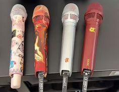 four microphones are lined up in a row and one is red, the other is silver