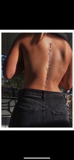 the back of a woman's body with a cross tattoo on it