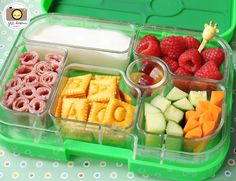 a green lunch box filled with fruit and veggies