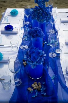 the table is set with blue flowers and place settings