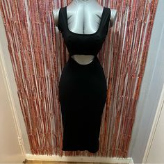 a mannequin wearing a black dress in front of a wall