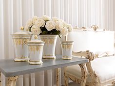 white roses are sitting in vases on a table next to two chairs and a couch