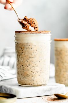 a person holding a spoon over a jar filled with oatmeal