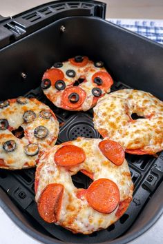 four mini pizzas with pepperoni and black olives in an air fryer