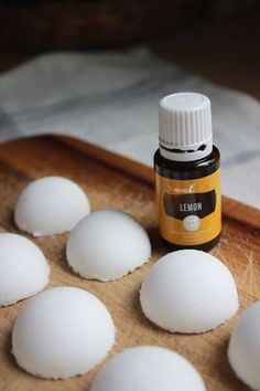 a wooden cutting board topped with lots of white balls of dough next to a bottle of lemon essential oil