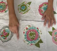 four pieces of cloth with flowers and leaves on them are being stitched together by someone's hands